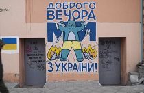 Sur un mur d'Odessa en Ukraine, un chat bleu affiche un sourire triomphant en piétinant un tas d'avions russes en flammes
