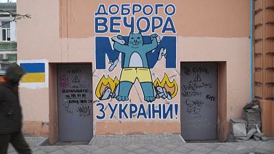 Sur un mur d'Odessa en Ukraine, un chat bleu affiche un sourire triomphant en piétinant un tas d'avions russes en flammes