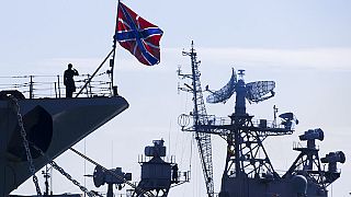 Orosz matróz szalutál a Moszkva fedélzetén a Pitlivij orosz hajónak jobbra, 2014-ben Szevasztopolban