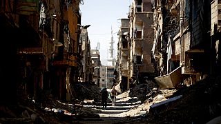 a man rides his bicycle through rubble in the Yarmouk Palestinian refugee camp, in Damascus, Syria.