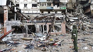 Στρατιώτης στέκεται μπροστά στα χαλάσματα κτιρίου στην υπό πολιορκία Μαριούπολη