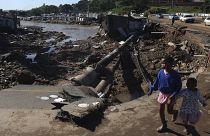 Unos niños caminan por una carretera dañada en un asentamiento informal en Durban, Sudáfrica, el jueves 14 de abril de 2022.