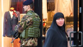 سيدة محجبة تسير أمام جندي يقوم بدورية في شارع روبيه بشمال فرنسا، في 13 يناير 2015.