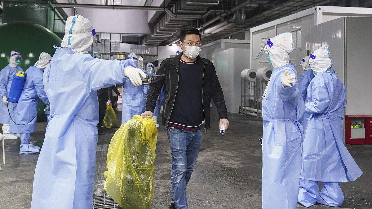 Pacientes de COVID-19 salen de un hospital improvisado en el Centro Nacional de Exposiciones y Convenciones de Shanghai, el jueves 14 de abril de 2022