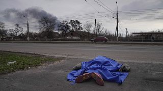 A body lies covered by a tarp in the street in Mariupol on 7 March 2022