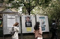 Teenagers run past torn presidential campaign posters of French President Emmanuel Macron and far-right candidate Marine Le Pen in Paris