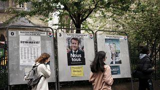 Teenagers run past torn presidential campaign posters of French President Emmanuel Macron and far-right candidate Marine Le Pen in Paris