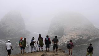 Pescadores miran una playa contaminada por un derrame de petróleo en el distrito de Ventanilla de Callao, Perú, 24 de febrero de 2022
