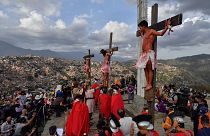 المؤمنون الكاثوليك يمثلون صلب يسوع المسيح خلال موكب الجمعة العظيمة في العاصمة الفانزويلية كاراكاس، 15 أبريل 2022.