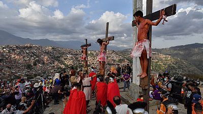 المؤمنون الكاثوليك يمثلون صلب يسوع المسيح خلال موكب الجمعة العظيمة في العاصمة الفانزويلية كاراكاس، 15 أبريل 2022.