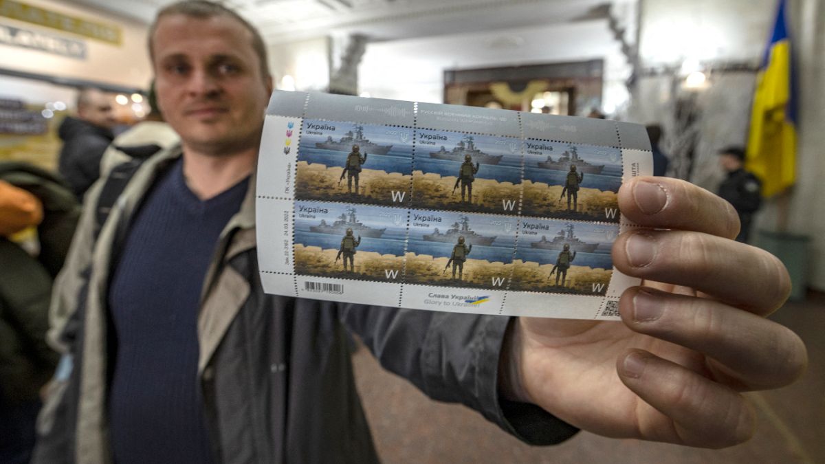رجلٌ أوكراني يقف في مكتب بريد وسط كييف ويعرض طوابع جديدة أصدرتها بلاده وتحمل صورة السفينة الروسية التي غرقت "موسكفا" 15 أبريل 2022.