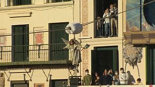 Un niño vestido de ángel desciende desde uno de los balcones de Tudela, en Navarra