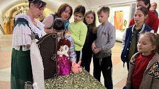 Children watch puppeteer Oleksandra Shlykova as she performs at the metro stations of Kharkiv.