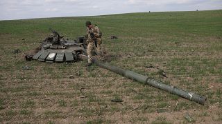 Un soldat ukrainien passant devant un char russe détruit près du village de Gusarovka, dans l'oblast de Kharkiv, en Ukraine orientale, le 16 avril 2022.