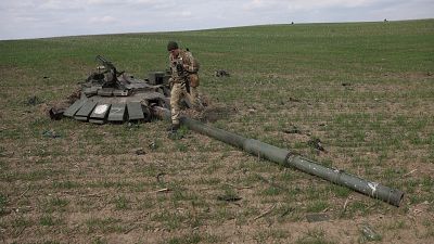 Un soldat ukrainien passant devant un char russe détruit près du village de Gusarovka, dans l'oblast de Kharkiv, en Ukraine orientale, le 16 avril 2022.