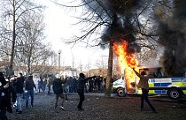 Манифестанты на фоне горящей полицейской машины. Акции протеста и беспорядки в Швеции 15/04/2022