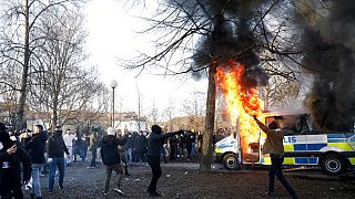 Манифестанты на фоне горящей полицейской машины. Акции протеста и беспорядки в Швеции 15/04/2022