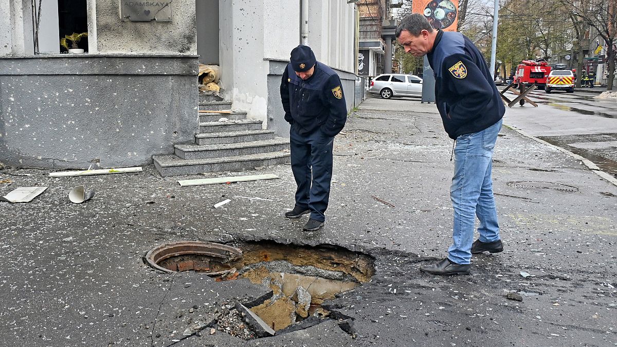 Rescuers look at crater following bombardment in central Kharkiv on April 17, 2022.