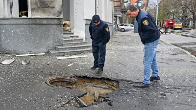 Rescuers look at crater following bombardment in central Kharkiv on April 17, 2022.