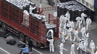 Workers in PPE unload groceries from a truck before distributing them to local residents under the COVID-19 lockdown in Shanghai, China, on April 5, 2022.