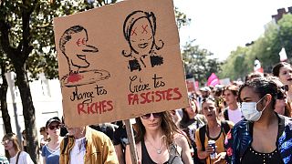 Auf der Pappe der Demonstrantin in Nantes steht unter Macrons Kopf: Friss Deine Reichen. Und unter Le Pens Kopf: Mach Deine Faschisten kalt.