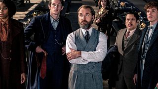 Stars (L-R) Jessica Williams, Callum Turner, Jude Law, Fionna Glascott, Dan Fogler & Eddie Redmayne in a scene from "Fantastic Beasts: The Secrets of Dumbledore"