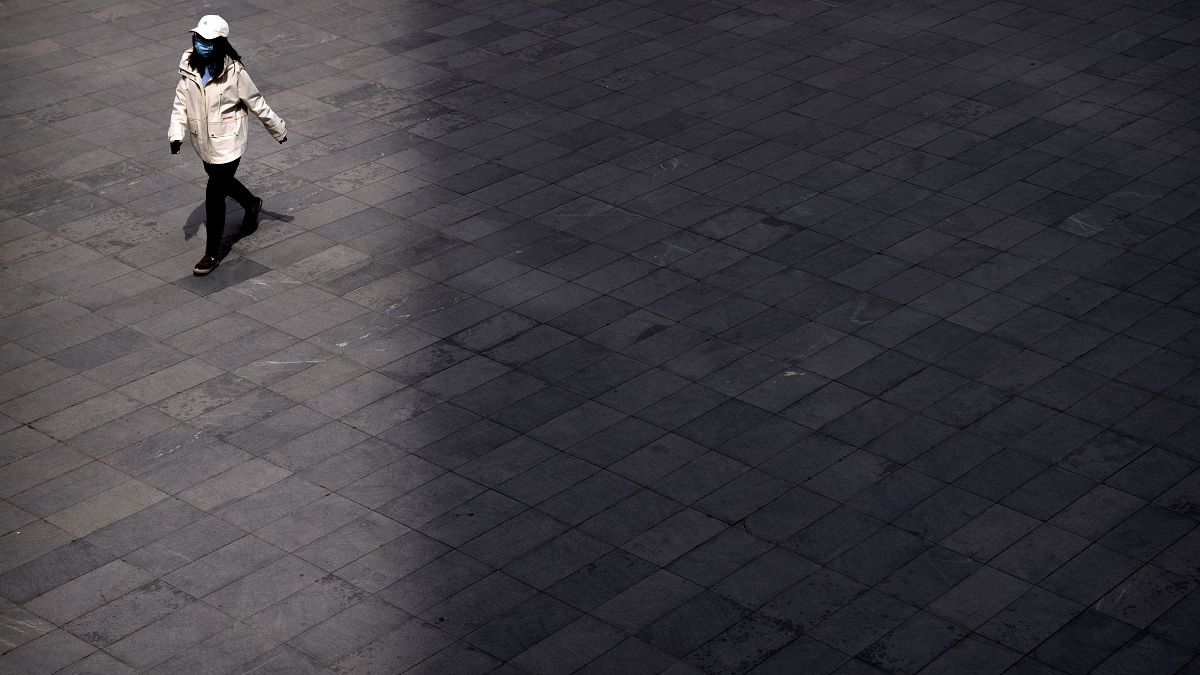 Eine Frau in Peking überquert einen Platz in Peking, 13.04.2022