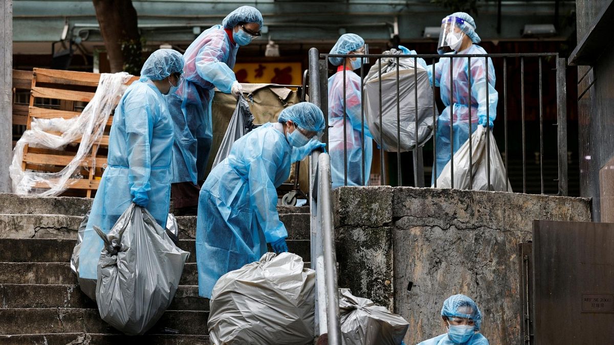 Cleaners wearing personal protective equipment (PPE) dump garbage outside a quarantine hotel during the coronavirus disease (COVID-19) pandemic, in Hong Kong.