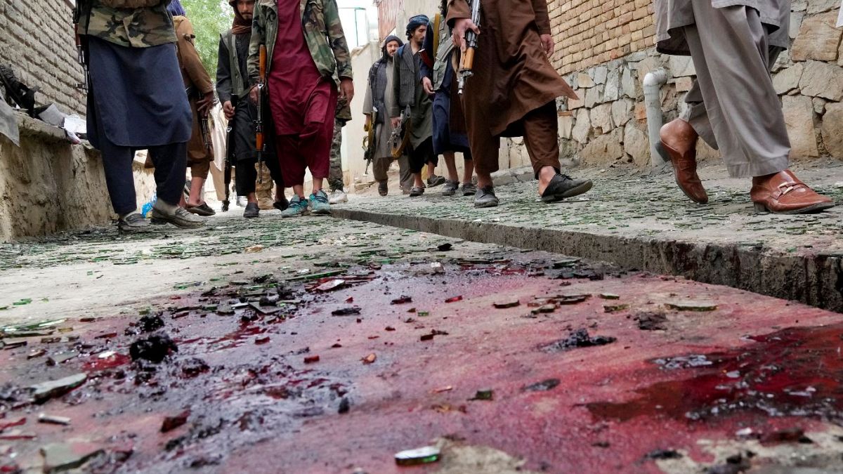 Taliban fighters stand guard on a blood-stained street at the site of the explosion.
