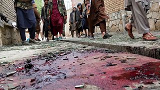 Taliban fighters stand guard on a blood-stained street at the site of the explosion.