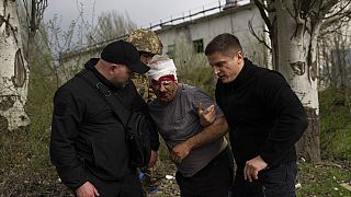 Un membre des forces de sécurité aide un homme blessé après un bombardement russe d'une usine à Kramatorsk, dans l'est de l'Ukraine, mardi 19 avril 2022