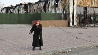 Пожилая женщина у разрушенного цеха Металлургического комбината им. Ильича