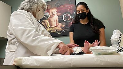 Dr. Sara Goza explains an infant's upcoming vaccinations to his mother in an exam room at First Georgia Physician Group Pediatrics in Fayetteville, Ga., Tuesday, Aug. 17, 2021