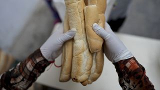 Una mujer reparte pan a la gente en un comedor social en Buenos Aires, Argentina, el martes 19 de abril de 2022.