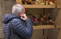 Un hombre se pone una mascarilla antes de entrar en una zapatería de Madrid (España), en el primer día sin la obligatoriedad de llevar mascarilla en interiores.