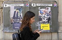 Junge Frau in Paris vor abgerissenen Wahlplakaten von Macron und Le Pen