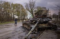 DUn homme à vélo à côté d'un char russe détruit, à Chernihiv (Ukraine), le 21/04/2022