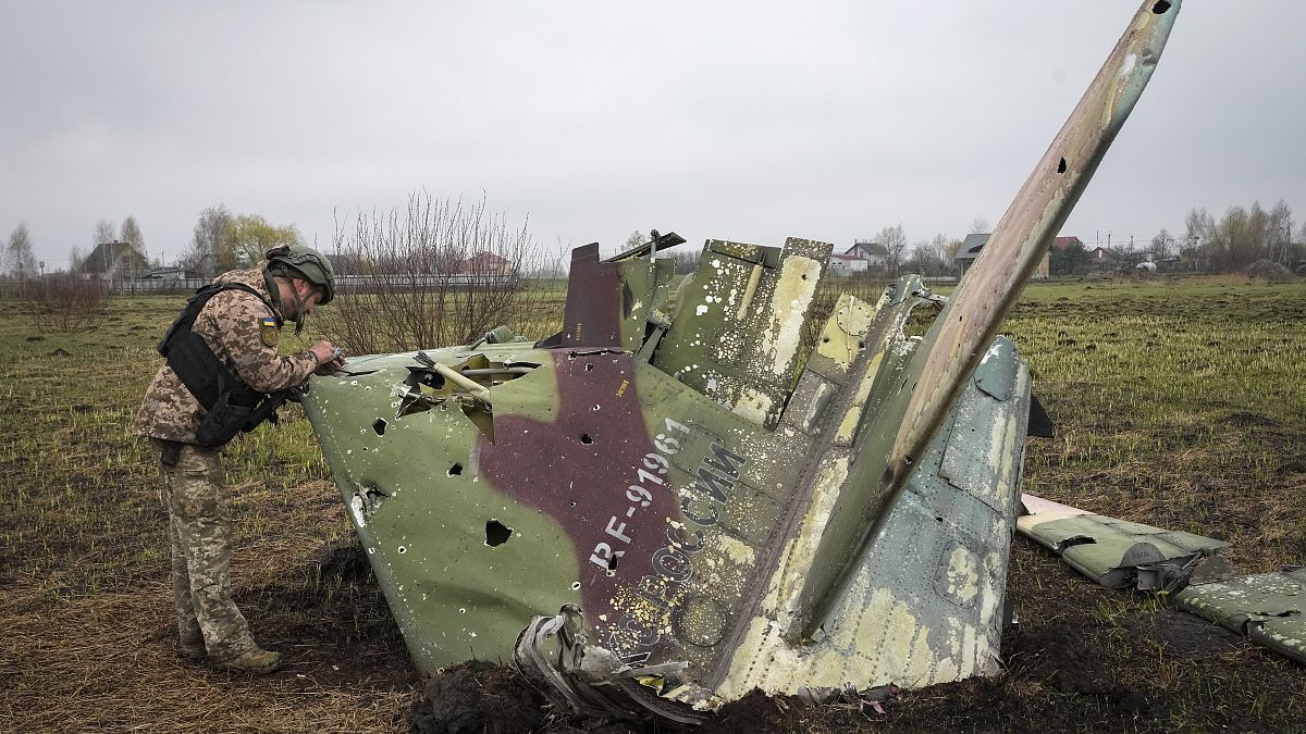 Украинский военный осматривает фрагмент сбитого российского самолета Су-25