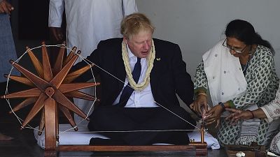 رئيس الوزراء البريطاني بوريس جونسون يجلس أمام آلة غزل النسيج الهندية