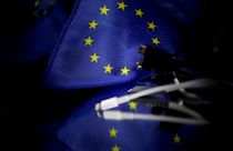 A picture taken on February 6, 2020 in Brussels shows plugs for mobile charger next to a European flag.