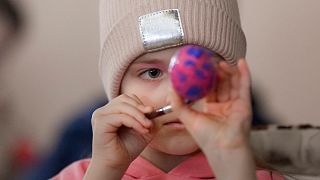 Criança refugiada ucraniana decora um ovo da Páscoa