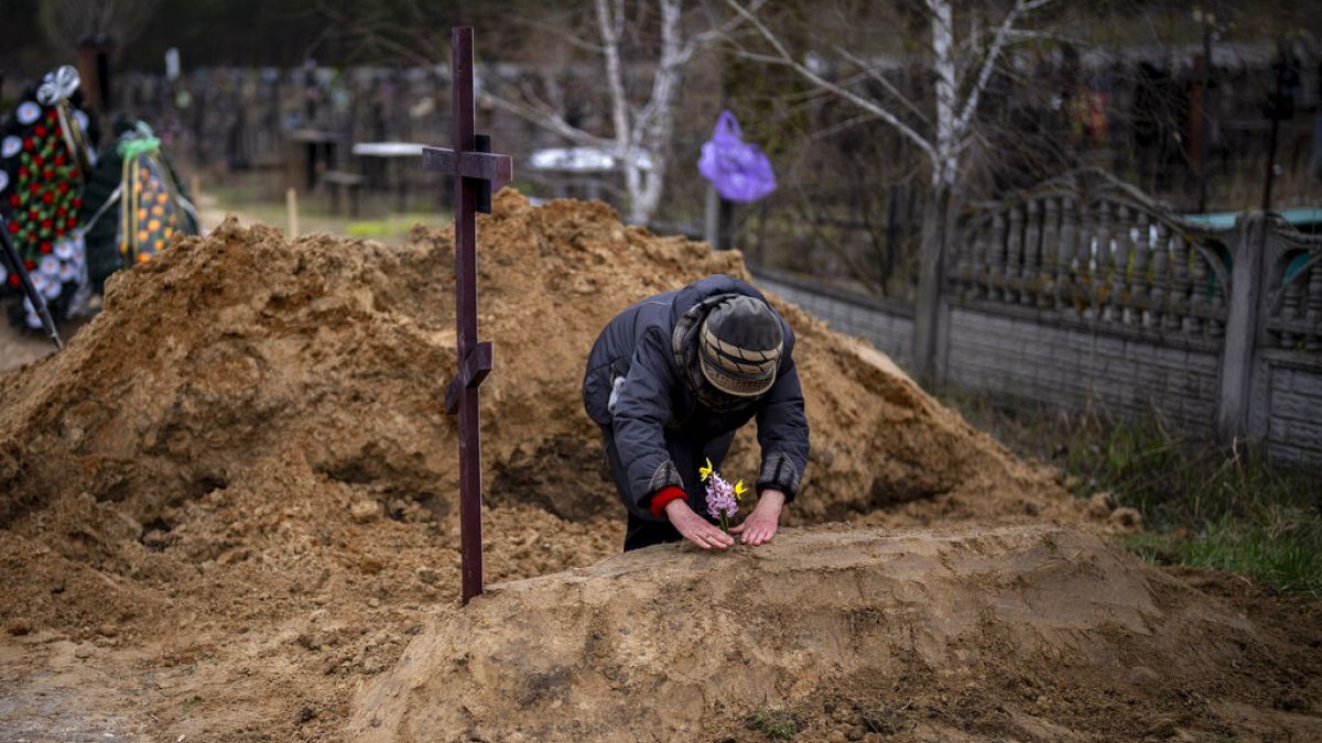 Γυναίκα γονιατίζει σε αυτοσχέδιο τάφο στην πόλη Μπούτσα στα περίχωρα του Κιέβου