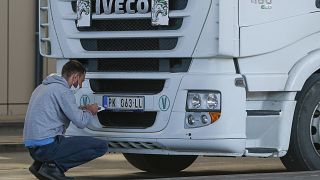 A truck driver places stickers on number plates at the Merdare border crossing on Monday, Oct. 4, 2021.