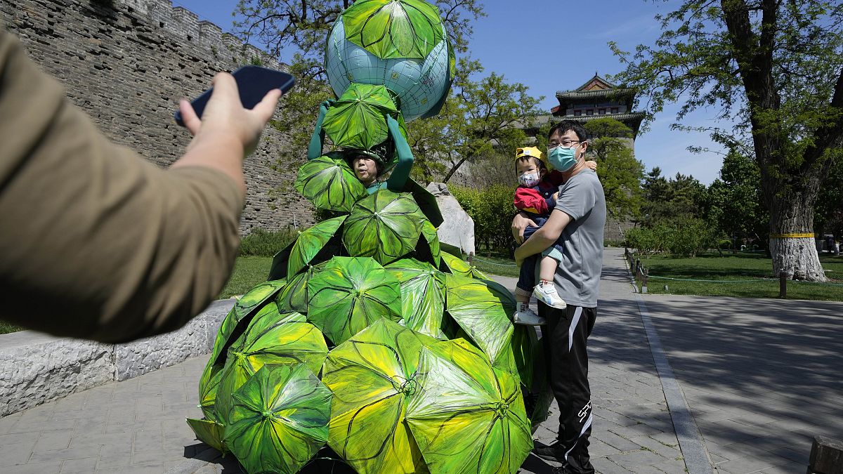 Китайская художница Кун Нин демонстрирует работу "Защитим Землю зонтиками из банановых листьев".