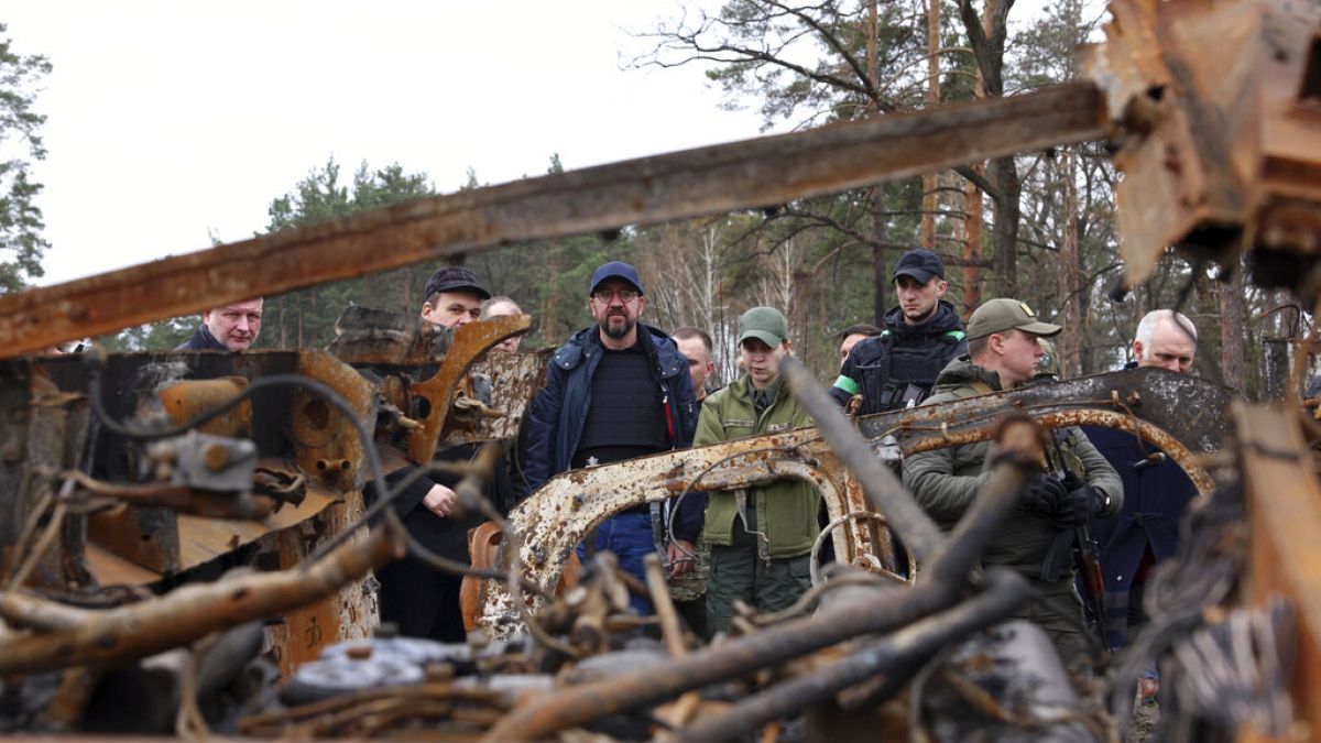 European Council President Charles Michel, center, looks at destroyed vehicles as he is given a tour of the region of Borodyanka, Ukraine, April 20, 2022. 
