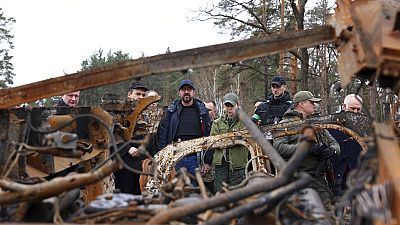 European Council President Charles Michel, center, looks at destroyed vehicles as he is given a tour of the region of Borodyanka, Ukraine, April 20, 2022. 