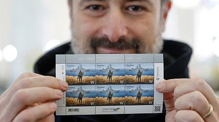 CEO of the Ukrainian post Ihor Smilianskyi demonstrates postal stamps showing Ukrainian service member and Russian warship depicting the sunken cruiser the Moskva.