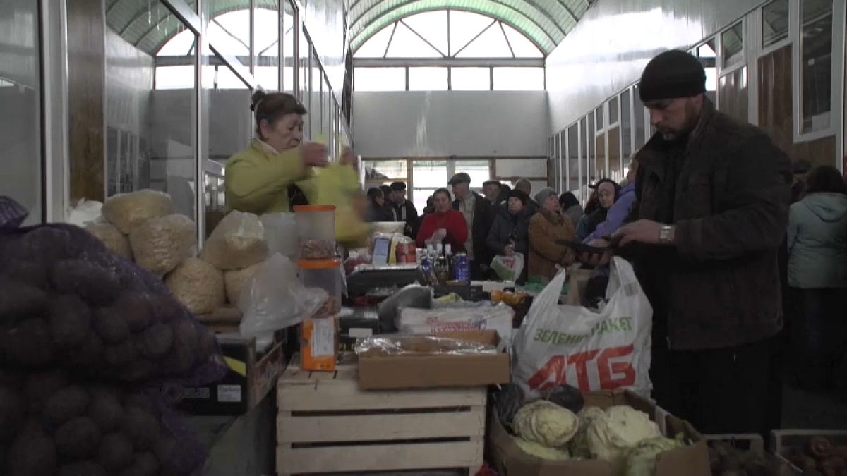 أوكرانيون يشترون احتياجياتهم من الخبز والمواد الغذائية في أحد الأسواق 