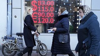 People walk past a currency exchange office screen displaying the exchange rates in Moscow's downtown, 28 February 2022