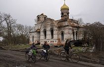 Vecinos de Lukashivka (Ucrania) pasan frente a la iglesia, destruida por los ataques rusos.